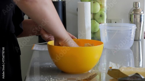 White professional baker combining large dough batch by hand in deep yellow bowl, vigorous mixing and kneading on kitchen worktop, commercial home hybrid setting