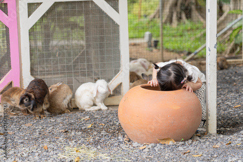little girl play hide and seek with a group of rabbit