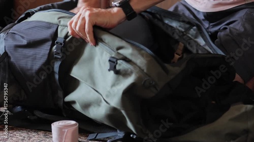 White man packing expedition duffel on carpet, careful hands slotting layers and accessories into inner pocket and adjusting buckles for balanced load before long voyage