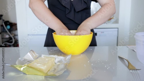 Baker preparing pastry, Person working on dough with butter and flour in modern kitchen, Individual kneading and mixing ingredients for baking in contemporary culinary
