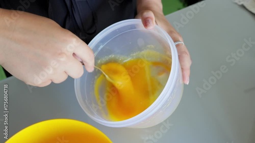 Bright orange egg mixture preparation, Vivid orange eggs combined in plastic bowl for baking, Energetic home baking scene with eggs blended in plastic dish on countertop