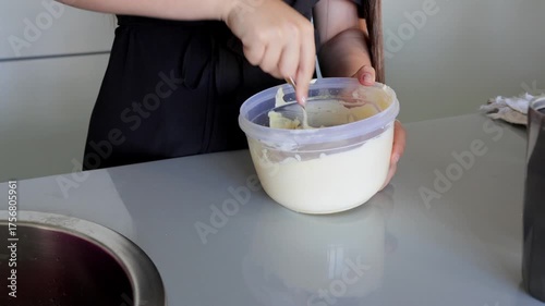 Mixing ingredients gently in bowl, Gently folding creamy mixture inside container for baking process, Calmly blending and leveling batter in plastic vessel for oven use