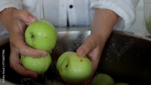 Fresh apple washing, Gentle water flow over vibrant green produce in kitchen, Seasonal orchard harvest ritual captured through detailed apple washing scene in kitchen