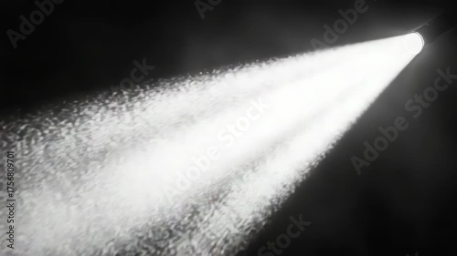 A powerful white spotlight illuminates a smoky, dark environment. Dust particles dance within the bright, focused beam.