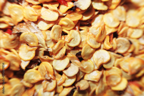 An extreme close-up, top-down macro shot of a pile of dry, yellow chili pepper seeds. The seeds fill the frame, creating a detailed texture background.