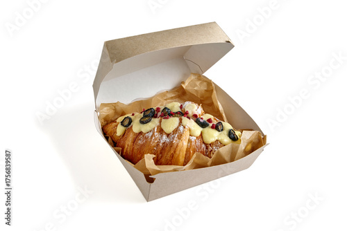 croissant topped with blueberry glaze and strawberry crumble in a cardboard lunch box