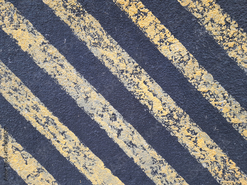 Textured Asphalt Surface with Yellow and Black Diagonal Stripes in Urban