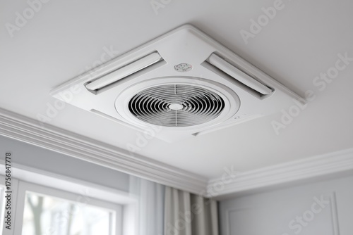 White ceiling-mounted air conditioner with central fan, angular design, installed in a room