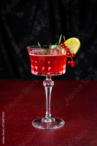 Christmas Sangria cocktail in elegant wine glass on dark table vertical photo, festive cranberry cocktail with lime