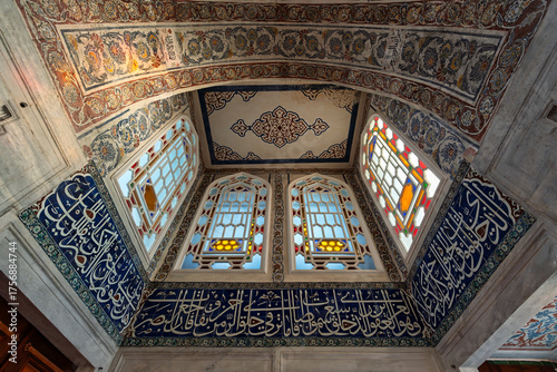 Interior of Sultan Ahmed I Tomb, Istanbul, Turkey. Features ornate Islamic patterns, colorful stained glass windows, and intricate calligraphy on blue tiles