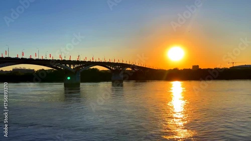 Gorgeous view from the Nizhnevolzhskaya Embankment in Nizhny Novgorod, Russia at the Oka River and the Kanavinsky Bridge, a calm romantic sunset mirrored on the glittering rippling waves of the river