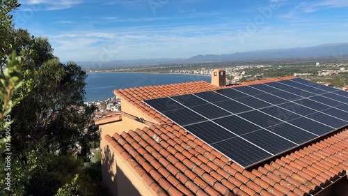 Solar batteries, Cell panels on house tiled roof in Spain on Mediterranean sea background. Solar electric panels. Photovoltaic Solar array system produce clean ecological electricity, Renewable energy