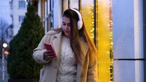 young woman standing outdoors on night neon street cafe illuminated for new year, drinking coffee to go