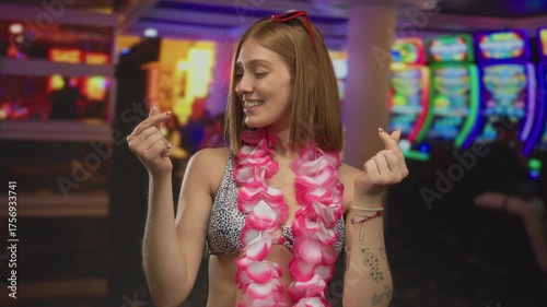 Wallpaper Mural Young blonde woman with bare arms forming a small heart shape with her fingers while smiling amid colorful slot machines in a casino; love affection happiness fun. Torontodigital.ca