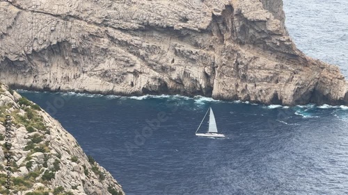 Sailboat navigating a rocky cliff coastline in mallorca