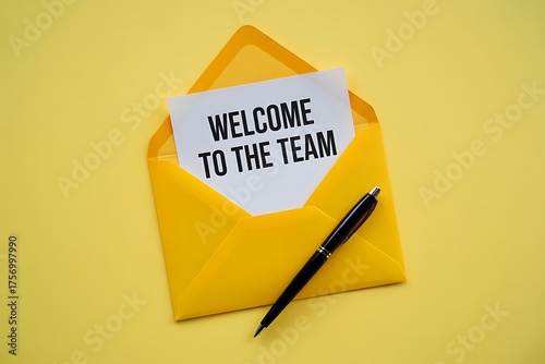 A bright yellow envelope lies open on a vibrant yellow surface revealing a white card with the handwritten message welcome to the team and a black pen