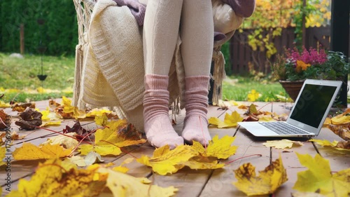 Cozy autumn morning on a wooden terrace with warm socks, blanket, and coffee. Peaceful fall mood, golden leaves, soft light, sweater weather lifestyle and comfort in nature.