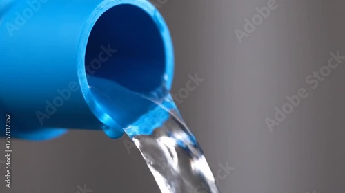 Water Flowing From Blue Plastic Pipe on Soft Gray Background Clean Water Concept