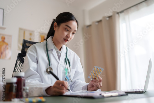 фотографія Female doctor writing prescription, holding medicine blister