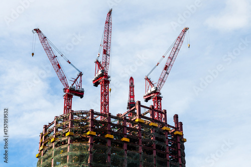 Low-angle view of cranes and steel structures of building construction with a blue sky background in Taiwan.
