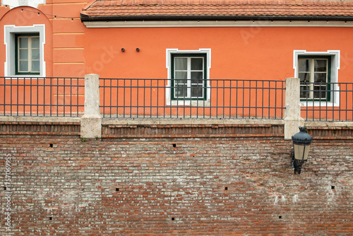 A fragment of a building with an orange facade and wooden windows, and a fragment of an old brick wall.