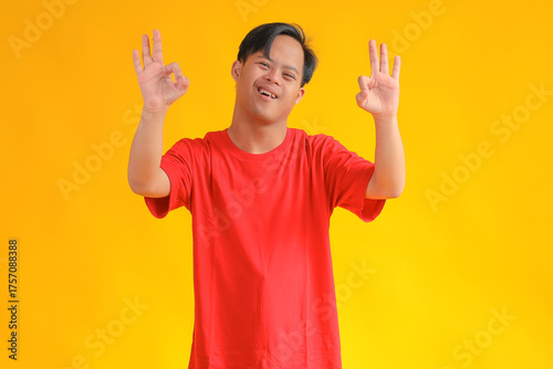 Smiling Young Man Gives Okay Hand Sign, Radiating Positivity Against Yellow Background