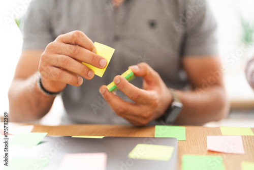 A person is holding and arranging colorful sticky notes on a desk, symbolizing planning and organization.