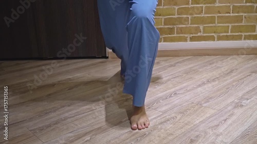 Medium shot front view young woman in home clothes exercising fitness lunges at home, authentic domestic workout routine, head not visible 4K video footage