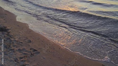 Close-up of sea tide with reflections of golden sunlight on sandy beach shore