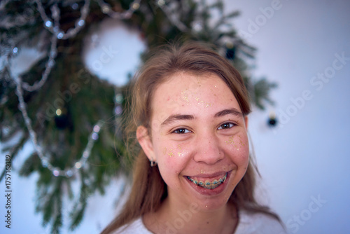 a portrait of a teenage girl with her face covered in gold glitter during a Christmas party at home