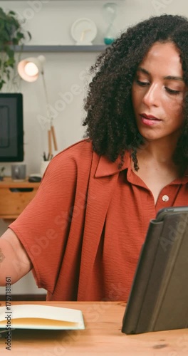 Focused Woman Working on Tablet and Taking Notes in a Modern Home Office