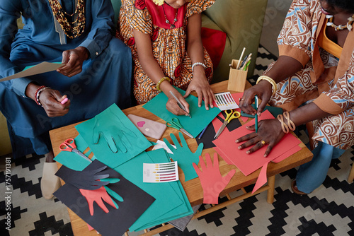 Photography Black woman, Black man, and Black child creating colorful paper hand cutouts tog