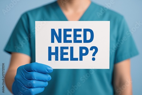 Healthcare professional in teal scrubs and blue gloves holds a clear sign asking 'NEED HELP?', symbolizing urgent medical support and compassionate care availability