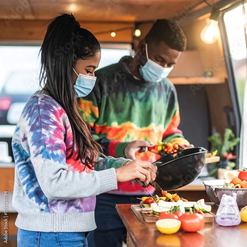 Couple in masks preparing skewers at a counter inside a van