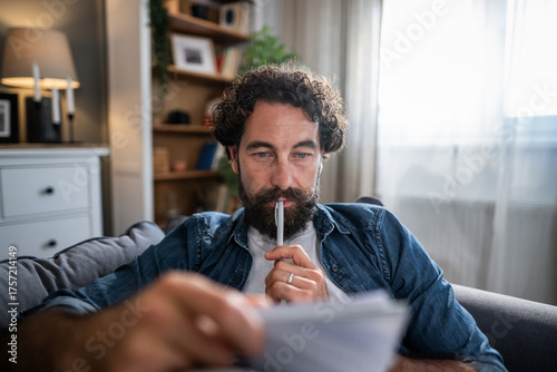 Foto Man thinking about document while planning finances at home