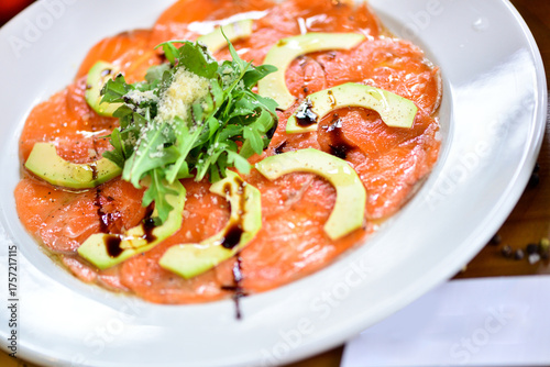 Salmon carpaccio with avocado on a white plate