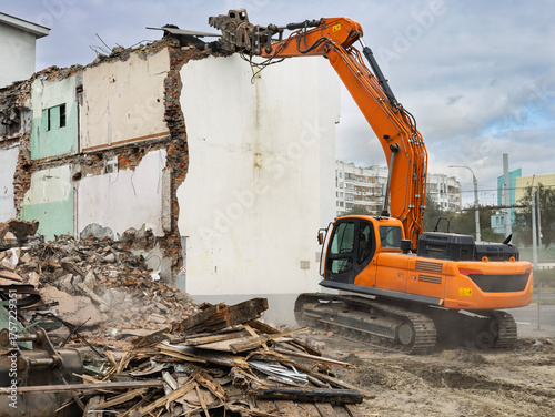 Картината върху платно Powerful excavator dismantling a building in an urban demolition site during day