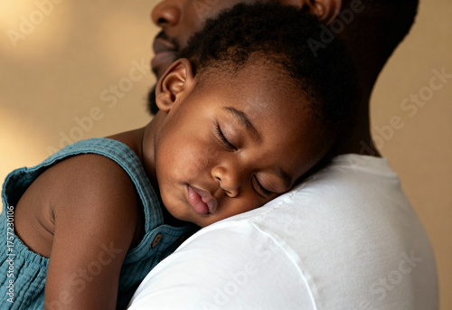 Peaceful toddler sleeping on father's shoulder, close embrace highlights warmth, care, and loving parent child bond indoors