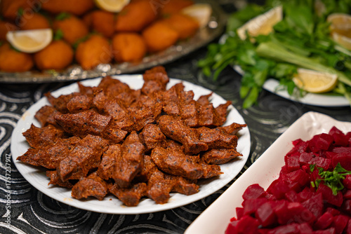 Plate of traditional cig kofte served with beet salad, greens and lemon slices. Traditional middle eastern and turkish cuisine kibbeh. Spicy bulgur raw meatballs. Table dinner concept
