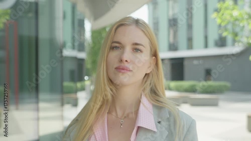 Charming Woman Fixing Hair And Smiling Confidently At Camera Outdoors