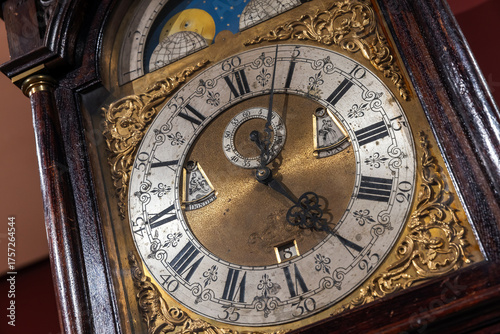 Photos A detailed shot of a vintage grandfather clock featuring a brass center,
