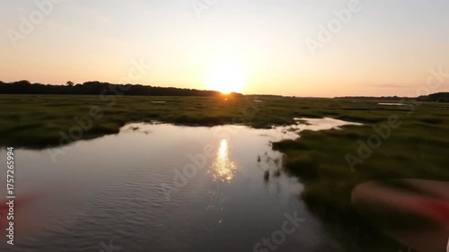 Aerial view of a wetland with sunlit grasses and reflective water surfaces