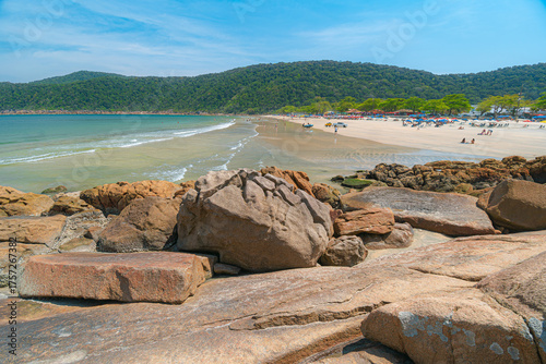 Guaiuba Beach, Guaruja SP, Brazil. Sunny day over the small bay with tranquil sea. Image of leisure and tourism on the Sao Paulo coast. Hills covered in Mata Atlantica vegetation frame the view.