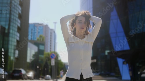 Confused young woman in stylish outfit waiting on modern city street portrait