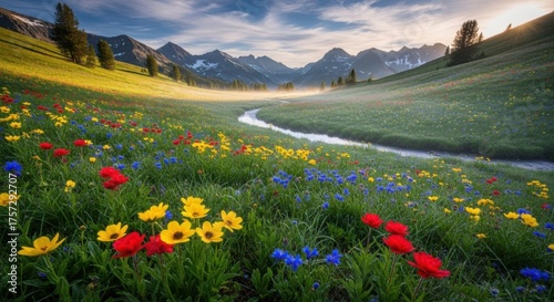 Idyllic mountain meadow with wildflowers stream and majestic peaks in serene morning light