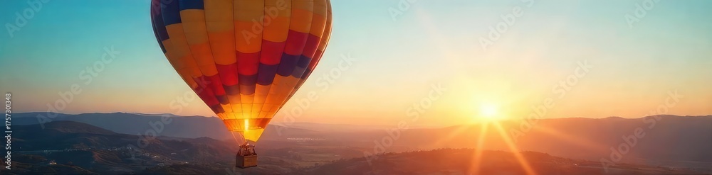 Obraz premium A vibrant hot air balloon ascends, bathed in the warm glow of sunrise, against a clear blue sky The basket is visible, and the landscape below is peaceful and expansive , peaceful, morning
