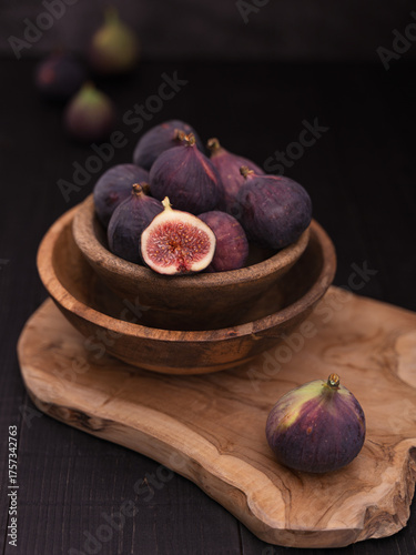 Half Sliced Fig on Wooden Board with Whole Figs and Vase in Background