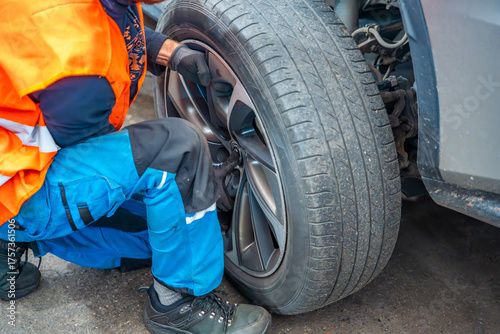 Mechanic removing a car wheel during seasonal tire change at an auto service shop. Timely winter tire replacement ensures road safety and compliance with regulations.