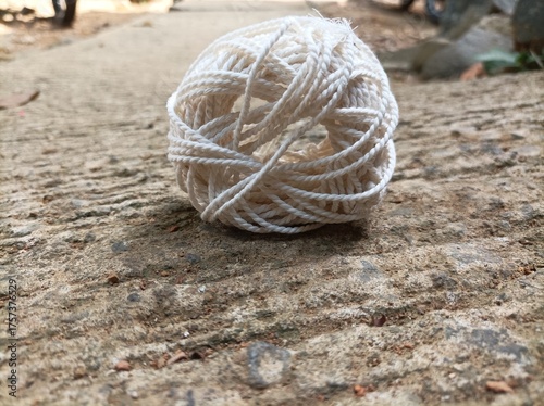 A white yarn ball placed on a rough concrete surface under natural light, showing fine texture, soft tones, and aesthetic composition in close-up view.