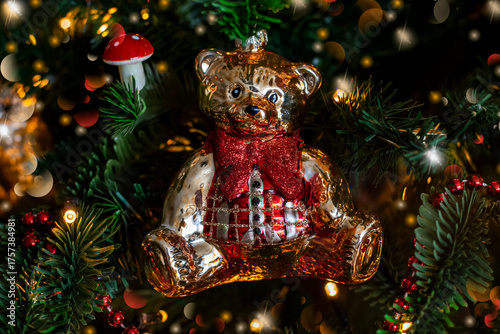 Teddy bear decoration on Christmas tree with festive lights garland, selective focus